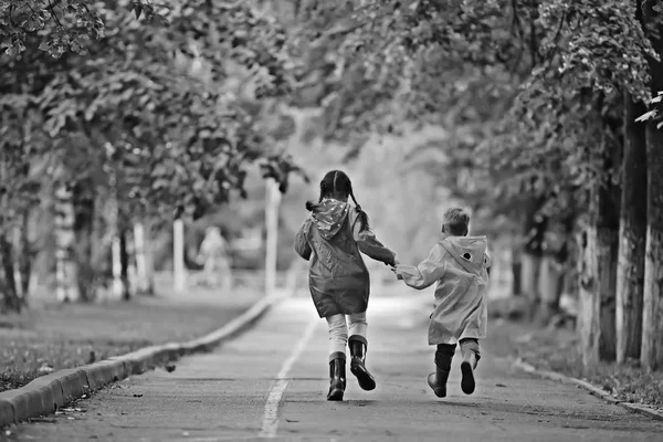 秋の公園で秋の散歩に男の子と女の子の子供 子供のためのレインコート — ストック写真