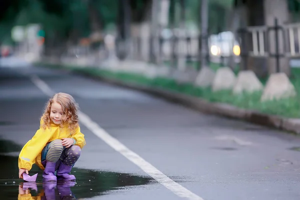 女孩在水坑里玩纸船 秋天在公园里散步 一个孩子在雨中玩耍 — 图库照片