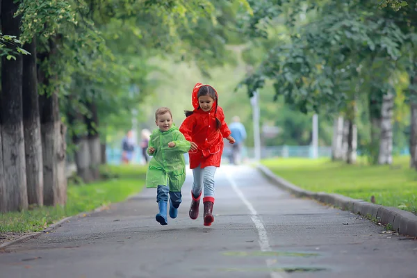 孩子们跑在雨衣 夏季公园 散步兄弟姐妹 儿童男孩和女孩 — 图库照片