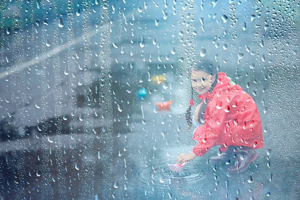 女の子は水たまりで紙ボートで遊ぶ 公園の秋の散歩 子供は雨の中で遊ぶ — ストック写真