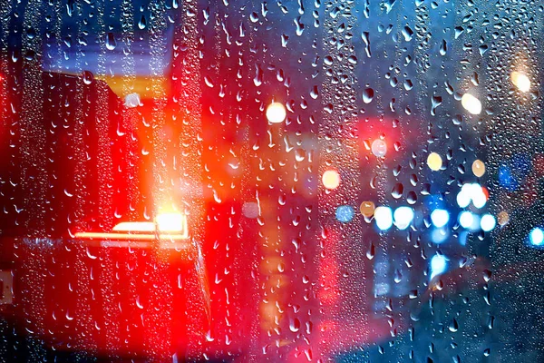 drops on glass auto road rain autumn night / abstract autumn background in the city, auto traffic, romantic trip by car