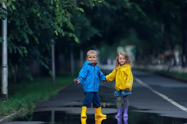 子供の兄弟姉妹が秋の雨を遊ぶ 10月の天気小さな子供たちが街を歩く — ストック写真