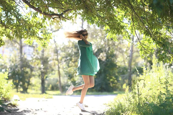 夏の遊び心のある大人の若い女の子がジャンプ 公園で陽気な美しいモデル 夏は短いスカートで見て — ストック写真