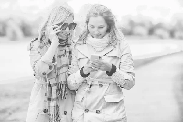 两个女孩看电话秋步 秋城公园外套 秋天时尚 — 图库照片