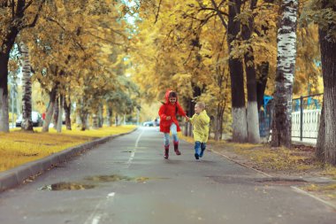 çocuklar sarı sonbahar parkı yağmur / eğlenceli yürüyüş sonbahar mevsimlik manzara ıslak koşmak