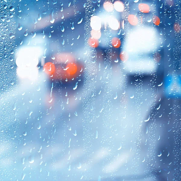 drops on glass auto road rain autumn night / abstract autumn background in the city, auto traffic, romantic trip by car