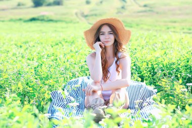 kız bir hasır şapka / yaz tatili ile bir alanda oturan, dinlenme genç yetişkin mutlu kadın