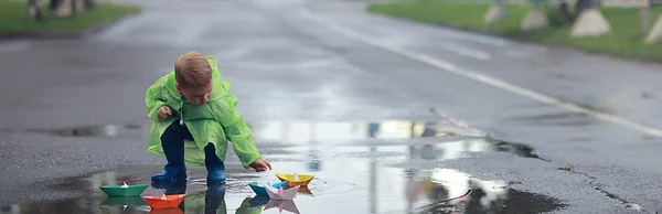 少年は水たまりでボートを遊ぶ 子供の頃 公園で秋のゲーム 散歩中の子供 — ストック写真