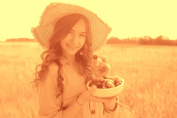 ピクニックフィールドの太陽を食べる女の子のラズベリー 晴れた夏のフィールドでラズベリーを食べる大人の若いモデル 幸せロマンスを楽しむ — ストック写真