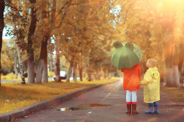 子供の兄弟姉妹が秋の雨を遊ぶ 10月の天気小さな子供たちが街を歩く — ストック写真