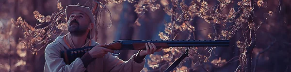 hunting man / hunter with a gun hunting in the autumn forest, yellow trees landscape in the taiga