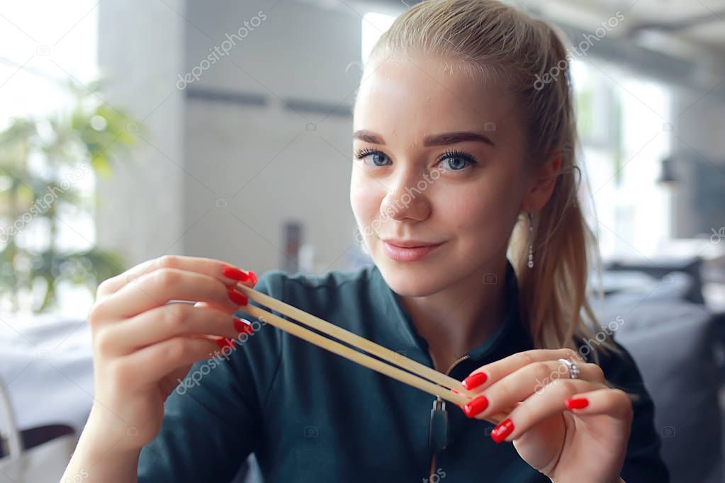 girl eats sushi and rolls in a restaurant / oriental cuisine, Japanese food, young model in a restaurant