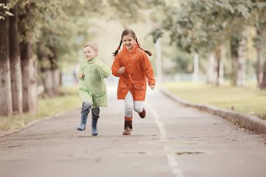 çocuklar sarı sonbahar parkı yağmur / eğlenceli yürüyüş sonbahar mevsimlik manzara ıslak koşmak