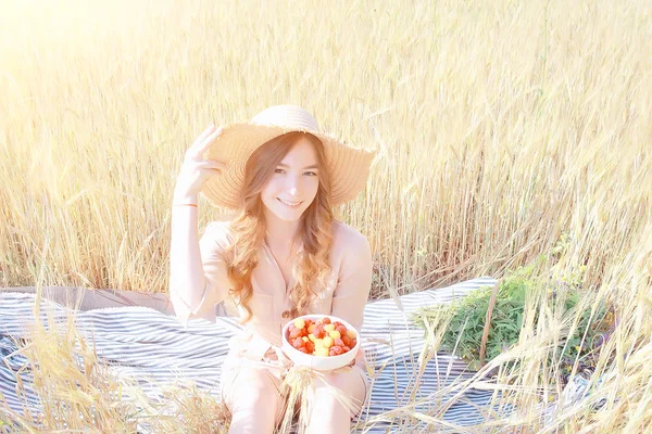 ピクニックフィールドの太陽を食べる女の子のラズベリー 晴れた夏のフィールドでラズベリーを食べる大人の若いモデル 幸せロマンスを楽しむ — ストック写真