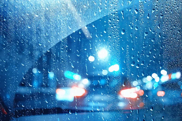 drops on glass auto road rain autumn night / abstract autumn background in the city, auto traffic, romantic trip by car