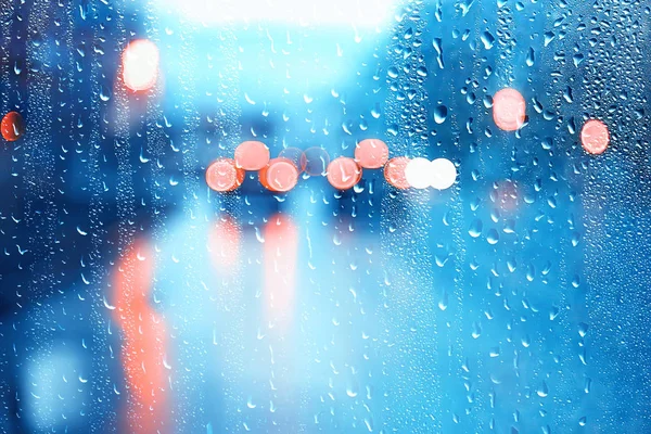 drops on glass auto road rain autumn night / abstract autumn background in the city, auto traffic, romantic trip by car