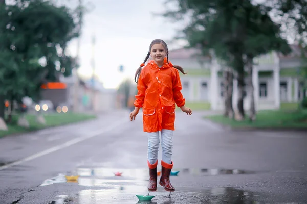 女孩在水坑里玩纸船 秋天在公园里散步 一个孩子在雨中玩耍 — 图库照片