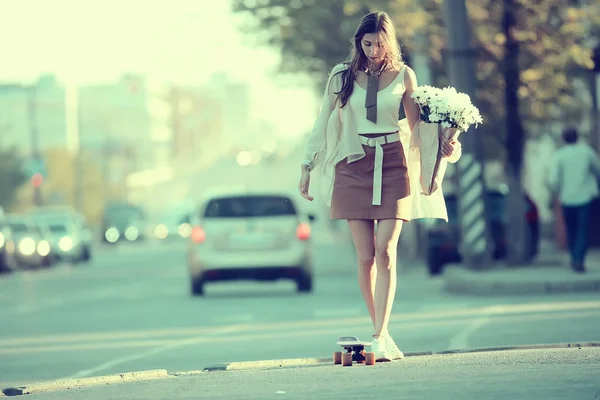 女孩骑溜冰在城市 模型年轻的成年女孩在街上充分成长 板在车轮上 — 图库照片