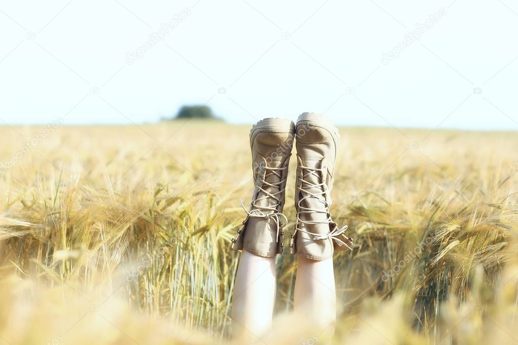 girl lies in the field with her legs up in boots / legs stick out in the field, the concept of leisure happiness