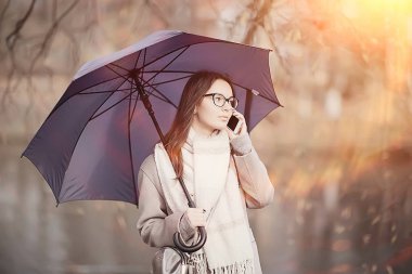 yağmur yağıyor / sonbahar hava durumu mesajında telefonda konuşan kadın, şemsiyeli bir model