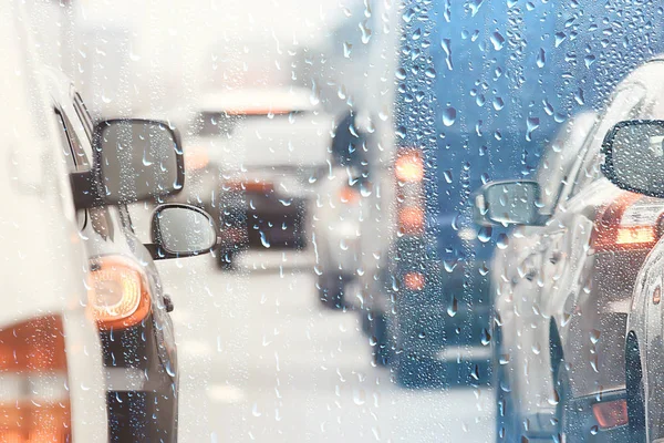 drops on glass auto road rain autumn night / abstract autumn background in the city, auto traffic, romantic trip by car