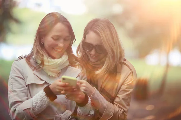 Duas Meninas Olham Para Telefone Outono Andar Outono Cidade Parque — Fotografia de Stock