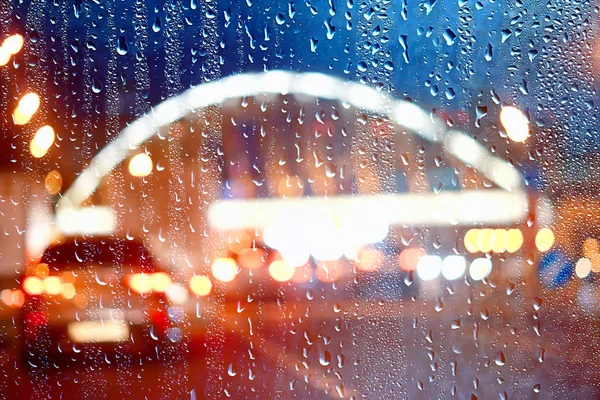 drops on glass auto road rain autumn night / abstract autumn background in the city, auto traffic, romantic trip by car