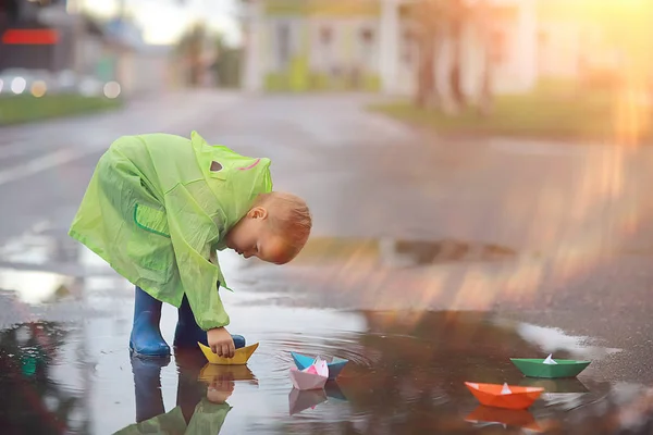 一个男孩在水坑里玩船 在公园里玩秋天的游戏 一个孩子在散步 — 图库照片