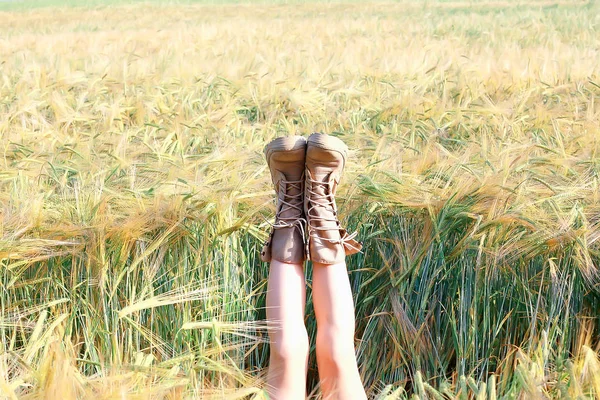 女の子はブーツで彼女の足を上げてフィールドに横たわっている フィールドに突き出て レジャーの幸福の概念 — ストック写真