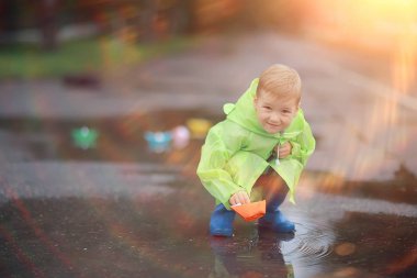 bir çocuk bir su birikintisi / çocukluk, yürüyüş, parkta sonbahar oyunu, bir yürüyüş bir çocuk tekneler oynar