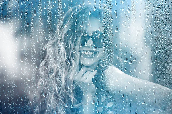 young adult girl outside the window view in the rain / raindrops on the glass warm autumn rain seasonal view