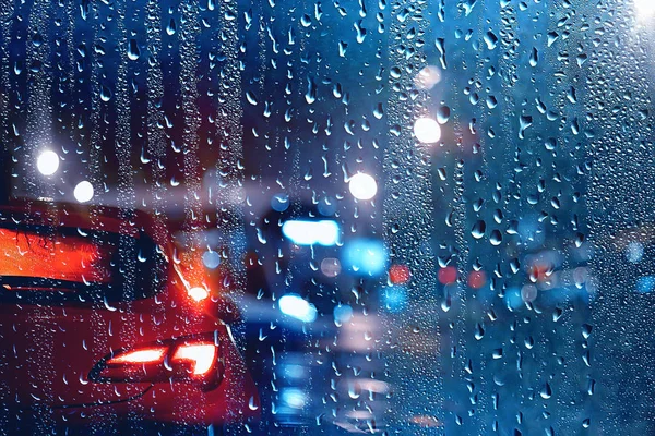 drops on glass auto road rain autumn night / abstract autumn background in the city, auto traffic, romantic trip by car