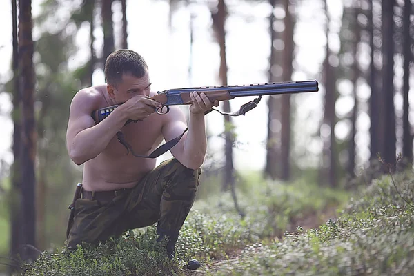 man goes hunting forest summer / landscape in the forest, huntsman with a hunting rifle hunts