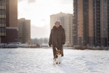 Kışın çayırda bir köpekle yürüyen neşeli kadın