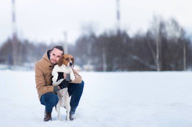 Kışın bir çayırüzerinde bir köpek ile ayakta neşeli adam