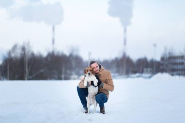 Kışın bir çayırüzerinde bir köpek ile ayakta neşeli adam