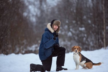 Kışın bir çayırüzerinde bir köpek ile ayakta neşeli adam
