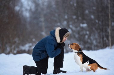 Kışın bir çayırüzerinde bir köpek ile ayakta neşeli adam
