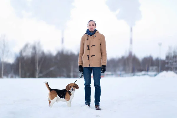 Homme joyeux avec un chien debout sur une prairie en hiver — Photo