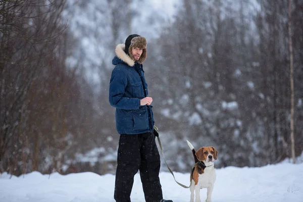 Homme joyeux avec un chien debout sur une prairie en hiver — Photo