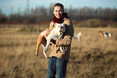 Genç mutlu avrupa gülümseyen ve gülerek elinde bir köpek İngiliz bulldog cins tutarak.