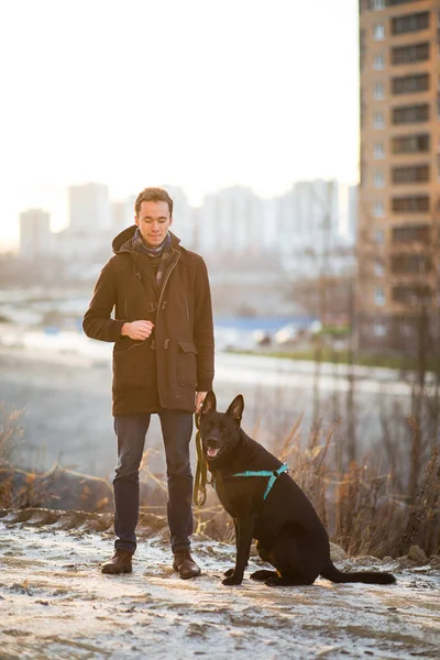 겨울 초원을 걷고 있는 괴물 개와 함께 있는 남자 — 스톡 사진