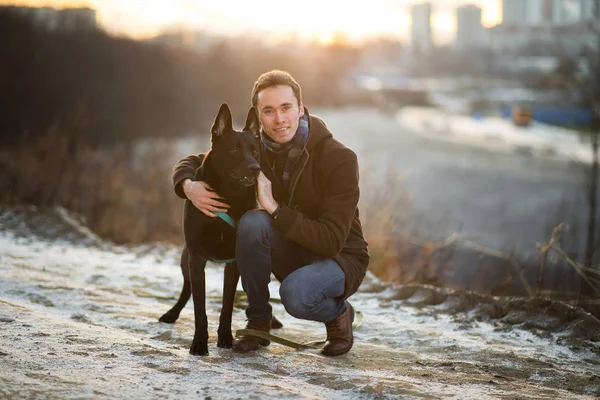 겨울 초원을 걷고 있는 괴물 개와 함께 있는 남자 — 스톡 사진