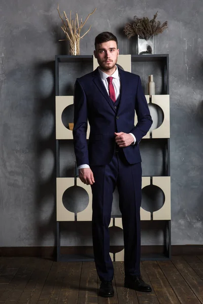 Elegant man in a three-piece suit stands in interior studio — Stock Photo, Image