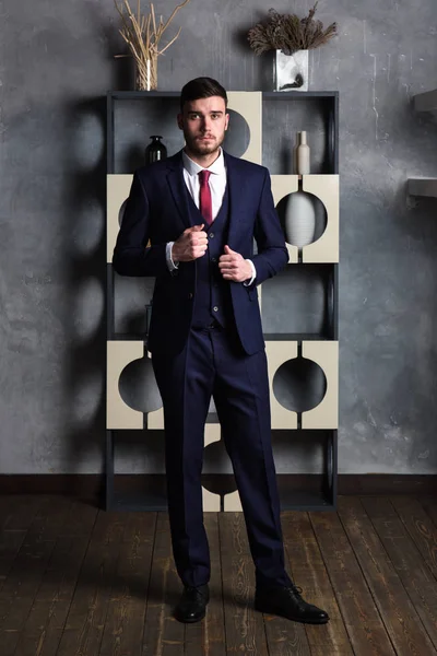 Elegante hombre en un traje de tres piezas se encuentra en el estudio interior —  Fotos de Stock