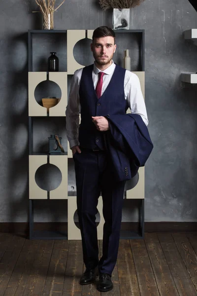 Elegante hombre en un traje de tres piezas se encuentra en el estudio interior —  Fotos de Stock