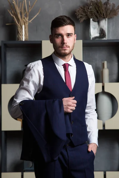 Elegant man in a three-piece suit stands in interior studio — Stock Photo, Image