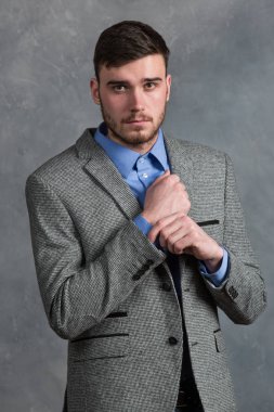 Yakışıklı şık genç adam gri arka plan üzerinde iç ayakta