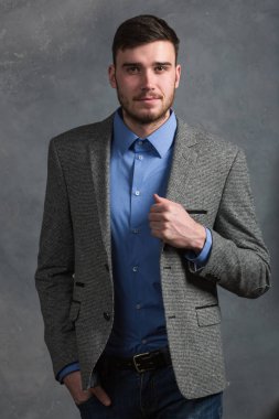 Yakışıklı şık genç adam gri arka plan üzerinde iç ayakta