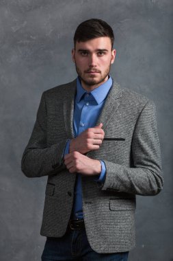 Yakışıklı şık genç adam gri arka plan üzerinde iç ayakta